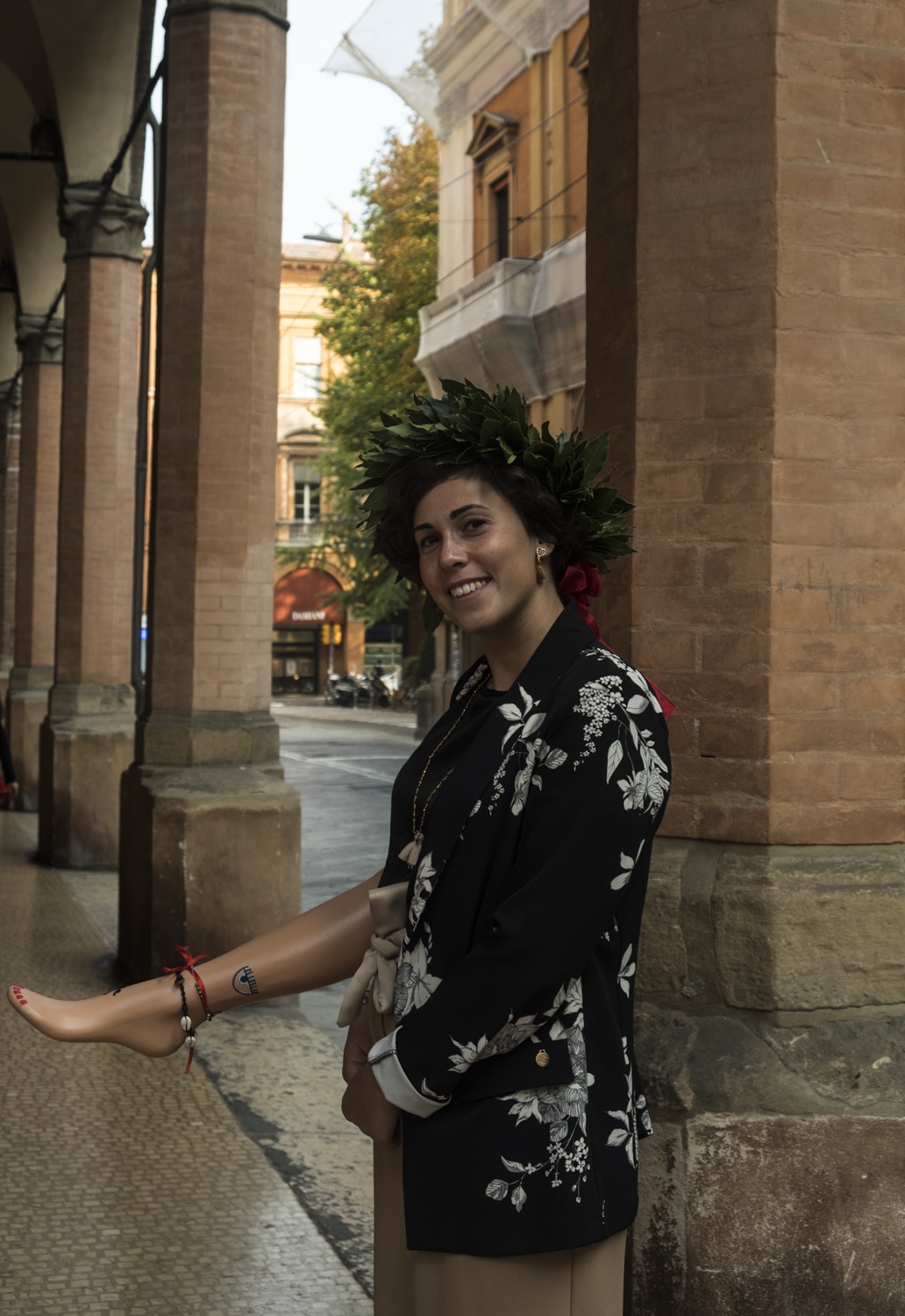 Female graduate in Bologna wearing laurel wreath and carrying a mannequin leg